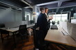© ultramansk - A bearded coworker and a young woman stand together at a workstation reviewing a tablet, the man gesturing at the screen in a dim after-hours coworking office in a bright modern coworking.
