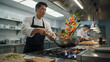 © graphicview35 - Professional asian chef cooking stirfry with vegetables and shrimp in a commercial kitchen
