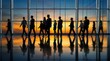 © Masque - Blurred silhouettes of business people walking through a modern office building with glass walls.