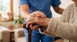 © Olga Ко - > Young caregiver in blue uniform holding hands of an elderly patient resting on a wooden walking cane, senior care and support concept.