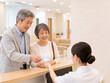 © morita - Smiling Elderly Couple Presenting My Number Card at Reception Counter