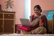 © IndiaPix - Happy woman shopping online with laptop using credit card at home