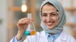 © AZ Studio - Smiling Muslim scientist in hijab and goggles holds flask with colorful liquids in lab