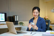 © Stella 16 - Happy beautiful businesswoman using a smartphone in a modern office workspace, working on an online project via mobile web services, typing on her cellphone and smiling.
