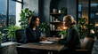 © HIJRAH - Two Professionals Discussing Business Matters In A Stylish Office With Plants
