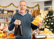 © JackF - Elderly male shopper buying beer and crispy chips in grocery store decorated for new year