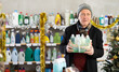 © JackF - Mature man examines product and doubts choice, chooses shower cosmetic kit present on Christmas Eve in household department. Buyer examines and selects product.