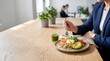 © Arip - Woman in blue blazer eating healthy salad with avocado and green smoothie at wooden table in office setting