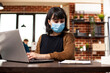 © DC Studio - Female analyst reading information on clipboard and typing on laptop in brick wall office, connecting office workflow, business planning and professional teamwork.
