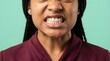 © Yassine - Close up portrait of a young woman showing intense frustration by clenching her teeth against a solid green studio background