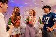 © Kawee - Group of diverse Generation Z friends enjoying a party in a cozy house.
