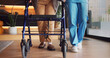 © peopleimages.com - Legs, rehabilitation and walker with people in clinic together for balance or stability. Healthcare, physiotherapy and walking frame on wheels for exercise or recovery of patient in wellness session