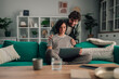 © Zamrznuti tonovi - Happy couple shopping online together from home using a laptop and credit card for e commerce