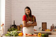 © IndiaPix - Smiling woman standing with rolling pin in kitchen