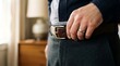 © Biru Langit Desember - Man fastening leather belt on dark trousers, getting ready for work or event, close up on hand and waist detail, professional attire preparation