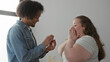 © Krakenimages.com - Man holds open ring box and slides ring onto woman's hand while she clasps hands to chest in building; joy love commitment.