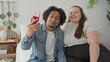 © Krakenimages.com - Man and plus size woman sit close on bed holding a smartphone for a selfie, smiling and leaning together in a bedroom; together joy.