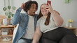 © Krakenimages.com - Man and plus size woman on bed holds smartphone showing screen while man puts arm around shoulder and raises hand in surprise in bedroom; joy together.