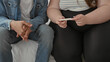 © Krakenimages.com - Woman holding pregnancy test, fingers and ring visible, hands clasped beside man sitting on bed in building; expectant hope.