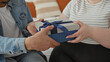 © Krakenimages.com - Man handing gift to woman on bed in building, hands meeting box and ring visible; intimacy love warmth.