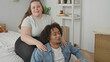 © Krakenimages.com - Plus size woman massaging man's shoulder as he leans back on bed in a cozy bedroom with shelf and plant beside them; comfort.