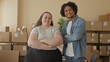 © Krakenimages.com - Woman and man smile while packing cardboard boxes and holding a parcel in a small shipping area inside a building; teamwork pride.