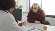 © Krakenimages.com - Woman covering her face with hand during medical consultation with doctor and stethoscope in a building; concern empathy.