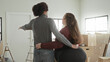 © Krakenimages.com - Man and plus size woman hug with arms around waist and pointing hand in apartment with moving boxes; new home love.