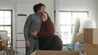 © Krakenimages.com - Man and plus size woman embrace and smile amid stacked moving boxes, a ladder and packing materials in a bright apartment room inside a building; love together.