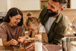 © La Famiglia - Happy family baking together, breaking eggs in kitchen