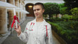 © Krakenimages.com - Woman doctor grimaces while holding a diploma with red ribbon, stethoscope visible, in building courtyard; career doubt.