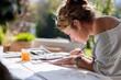 © Marc Romanelli - young woman artist working on a watercolor drawing outdoors