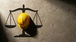 © spyrakot - Yellow construction helmet casting scales of justice shadow on concrete wall