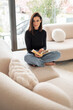 © gzorgz - Full length of a brunette haired young woman reading a book in her modern home