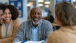 © forenna - Financial counselor seated across from a young couple in a community center office, folders open on the table, workplace financial wellness program, credit counseling, employee