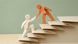 © Concept - Origami paper figures helping each other up folded paper stairs showing creative teamwork and design mentorship