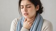 © TransPicHub - A young woman with a scarf looks distressed and holds her throat, indicating discomfort or pain.