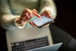 © Davor - Person texting on smartphone while working on laptop at home