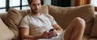© ckybe - In a bright modern living room, a young man in casual attire scrolls through his smartphone while relaxing on a sofa.