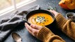 © MstMahofuza - Warm and cozy pumpkin soup in a black bowl with fresh herbs