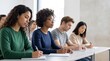 © Eve - Diverse young female students writing notes in college classroom seminar, multiethnic corporate education training, professional development course, female empowerment learning concept
