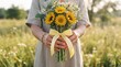 © Matheus - Person holding a vibrant sunflower bouquet tied with a yellow ribbon in a lush outdoor field