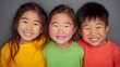 © Anuson - Three happy Asian children smiling brightly in a colorful studio portrait