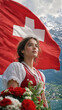 © Margarita Ratatosk - Woman in traditional Swiss clothes holding flower bouquet against national flag of Switzerland. Young girl celebrating Swiss National Day in Alps. Patriotism and Alpine culture concept.