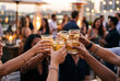 © Meow Creations - Group of diverse friends raising glasses for a toast with cocktails at an outdoor rooftop party