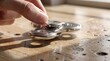© naevermillion - A person playing with a metallic fidget spinner on a wooden table.