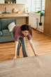 © La Famiglia - Woman preparing to clean living room area rug