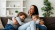 © Ashrafunnahar - Mother laughing with her two children on a sofa
