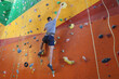 © New Africa - Athletic young man climbing wall in gym, back view