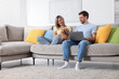 © New Africa - Happy couple with their adorable dog and laptop on sofa at home